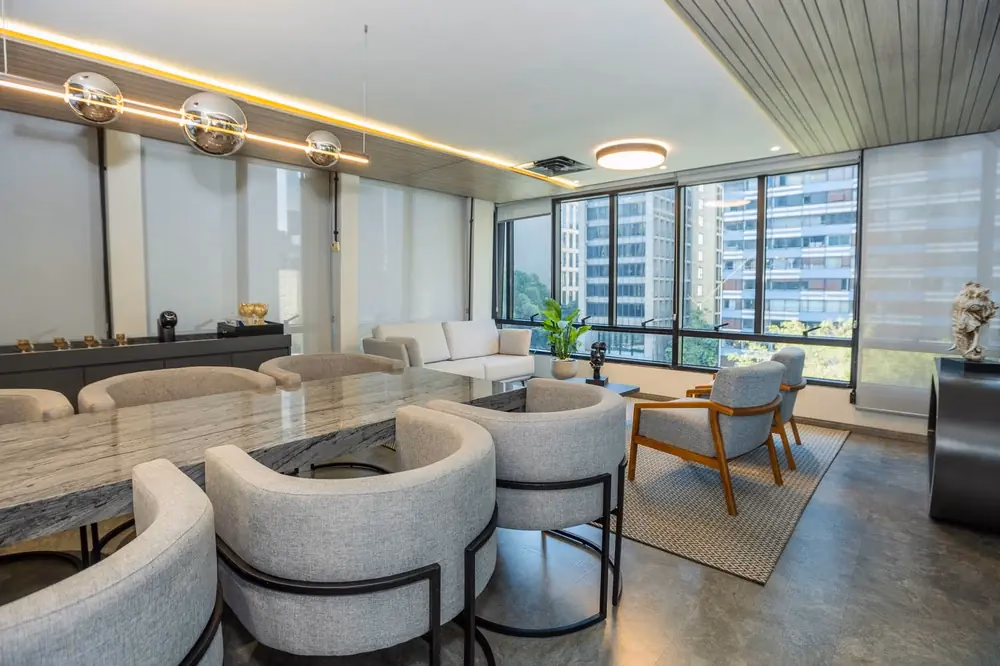 Sala de estar corporativa da UNE Eventos em São Paulo com poltronas e vista da cidade