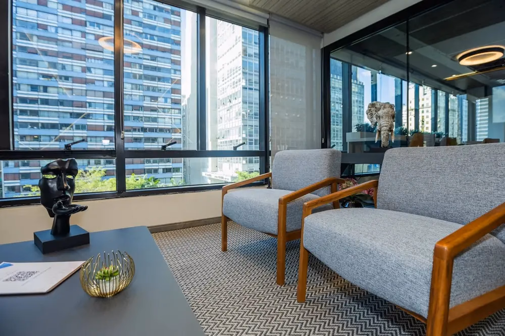 Sala de estar corporativa com poltronas e vista panorâmica de São Paulo