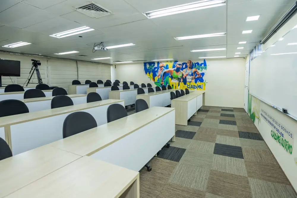 Sala de treinamento com cadeiras dispostas em fileiras e painel colorido na parede