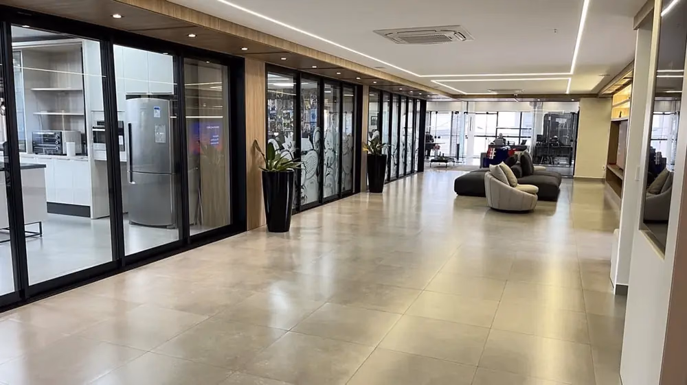 Sala corporativa ampla com piso de madeira e portas de vidro para eventos empresariais
